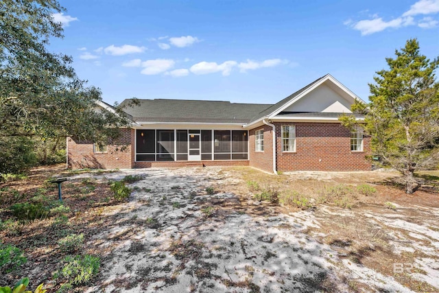 rear view of property with brick siding and a sunroom