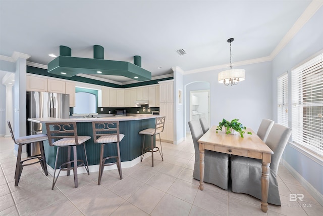 kitchen featuring light tile patterned floors, visible vents, an inviting chandelier, ornamental molding, and a center island