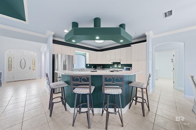 kitchen featuring a breakfast bar area, white cabinets, light countertops, and freestanding refrigerator