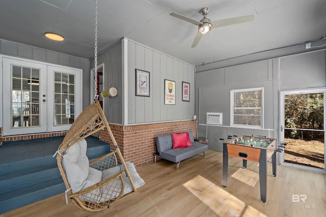 game room with ceiling fan, french doors, wooden walls, and light hardwood / wood-style flooring