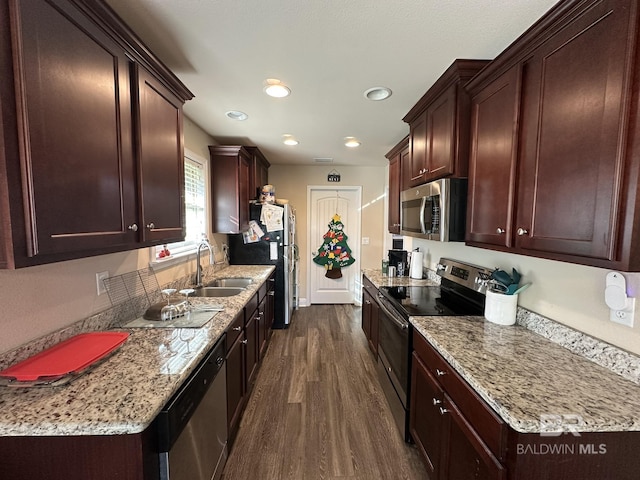 kitchen with light stone counters, sink, dark wood-type flooring, and appliances with stainless steel finishes