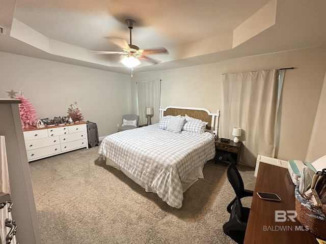 carpeted bedroom with a tray ceiling and ceiling fan