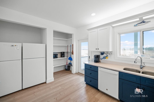 kitchen with white cabinetry, sink, light hardwood / wood-style floors, blue cabinetry, and white appliances