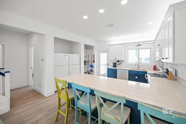 kitchen featuring sink, white appliances, white cabinets, blue cabinets, and kitchen peninsula