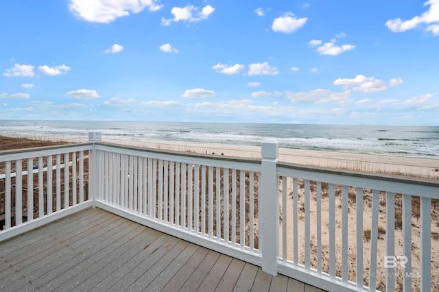 wooden deck featuring a water view and a beach view