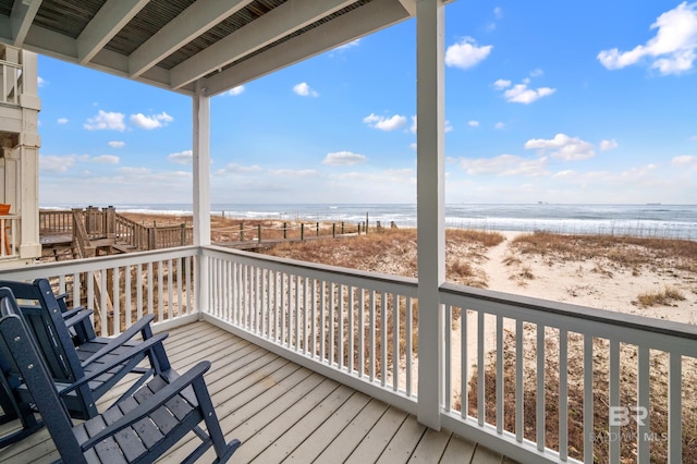 wooden deck featuring a beach view and a water view