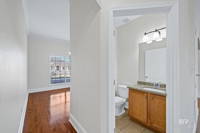 bathroom with toilet, vanity, ornamental molding, and hardwood / wood-style floors