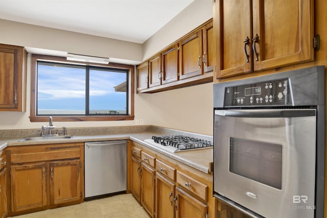 kitchen featuring brown cabinetry, a sink, light countertops, and stainless steel appliances