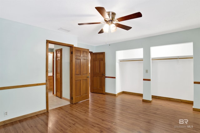 unfurnished bedroom with visible vents, baseboards, multiple closets, and wood finished floors