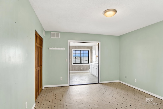 empty room with baseboards, visible vents, and light floors