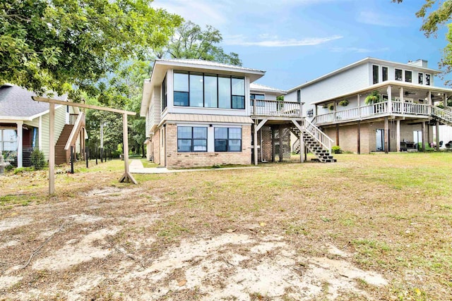 rear view of house with brick siding, a yard, stairway, and a deck