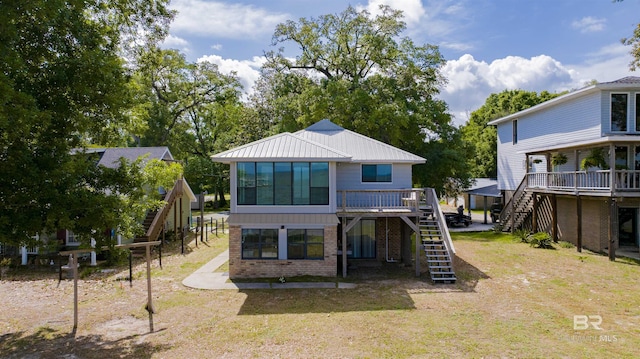 back of house with stairs, a deck, and brick siding