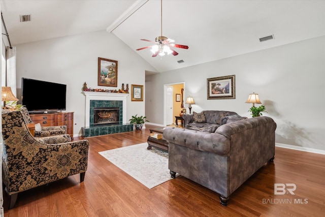 living room with ceiling fan, hardwood / wood-style floors, high vaulted ceiling, and a tile fireplace