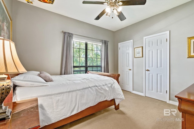 carpeted bedroom with ceiling fan and two closets