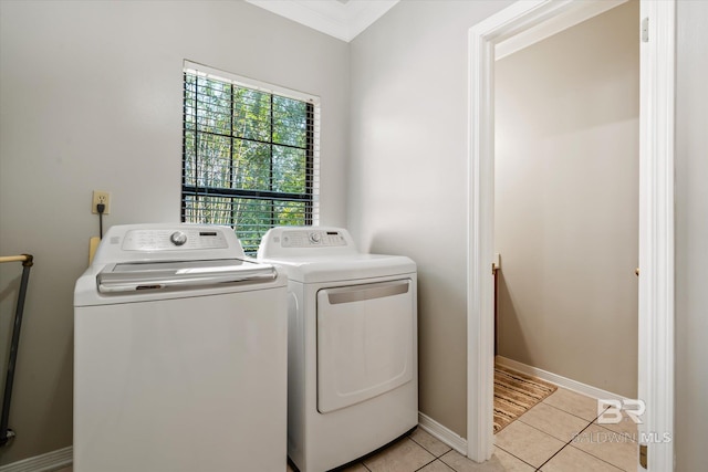 clothes washing area featuring light tile patterned flooring, crown molding, and washing machine and clothes dryer