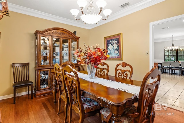 dining space featuring wood-type flooring, crown molding, and an inviting chandelier