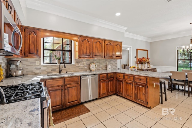 kitchen with tasteful backsplash, sink, stainless steel appliances, kitchen peninsula, and ornamental molding