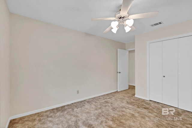 unfurnished bedroom with light carpet, ceiling fan, and a closet