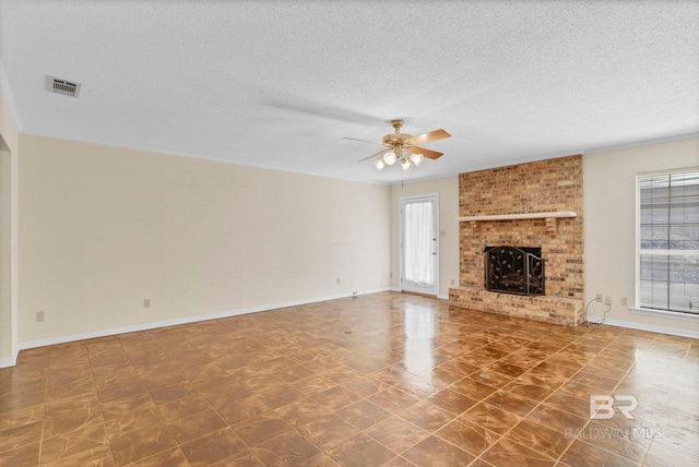 unfurnished living room featuring ceiling fan, a brick fireplace, and a textured ceiling