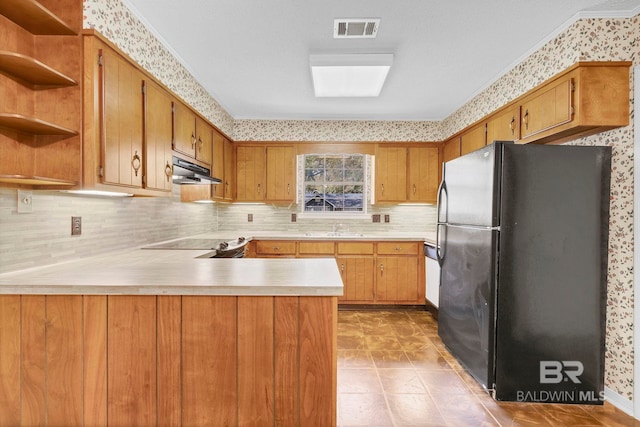 kitchen featuring sink, black refrigerator, kitchen peninsula, decorative backsplash, and cooktop