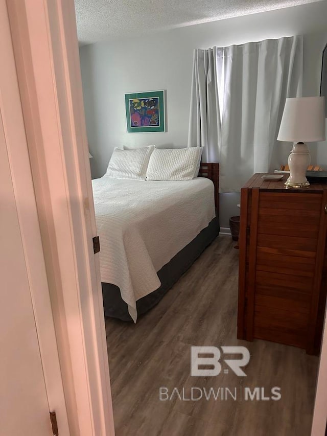 bedroom with dark wood-type flooring and a textured ceiling