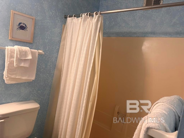 bathroom with a shower with shower curtain and toilet