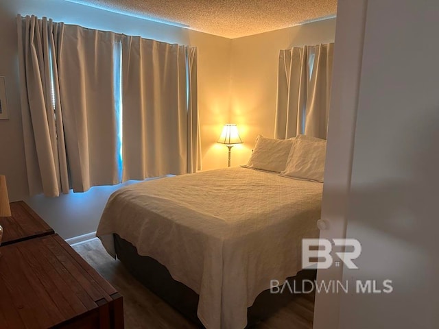 bedroom with a textured ceiling and dark wood-type flooring