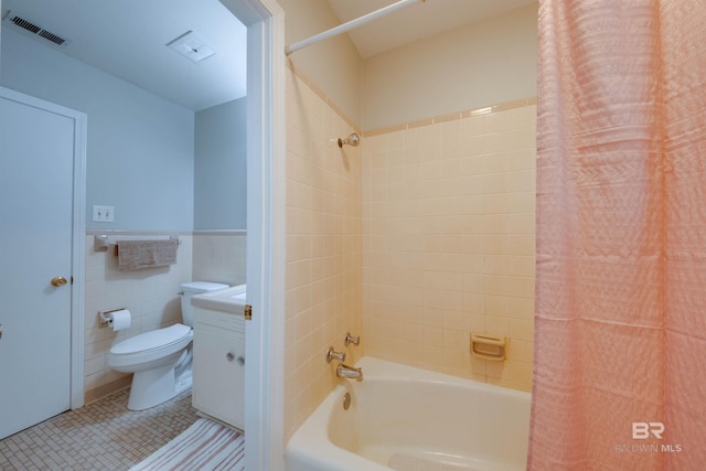 full bathroom with shower / bath combination with curtain, vanity, tile patterned floors, toilet, and tile walls