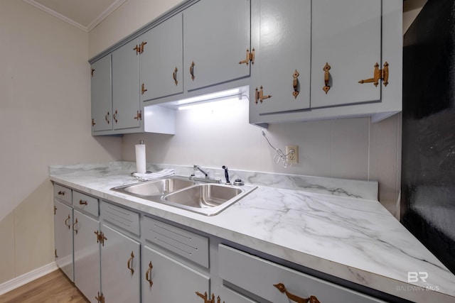 kitchen featuring light wood-type flooring, gray cabinets, sink, and crown molding