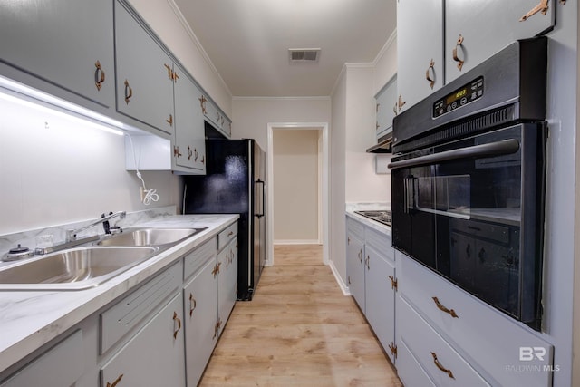 kitchen featuring light hardwood / wood-style floors, black appliances, sink, and crown molding