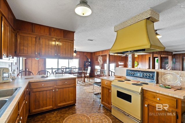 kitchen with wooden walls, range with electric stovetop, dark parquet flooring, island exhaust hood, and kitchen peninsula