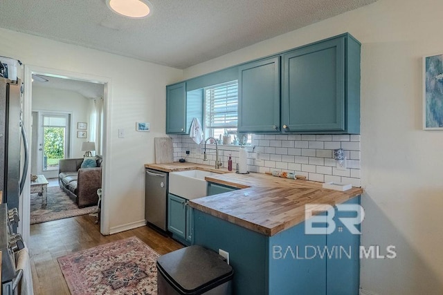 kitchen featuring sink, appliances with stainless steel finishes, butcher block counters, dark hardwood / wood-style flooring, and decorative backsplash