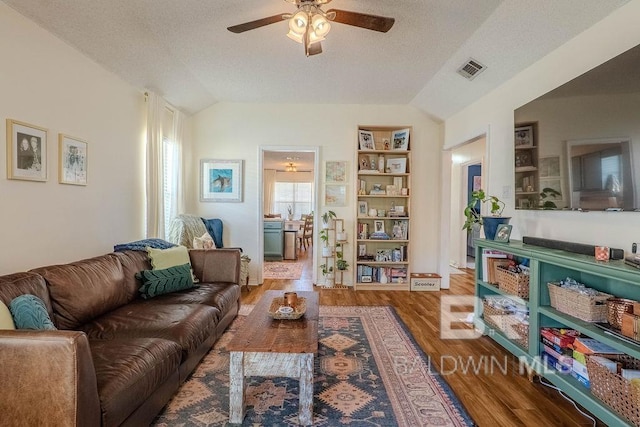 living room featuring lofted ceiling, wood-type flooring, ceiling fan, and a textured ceiling