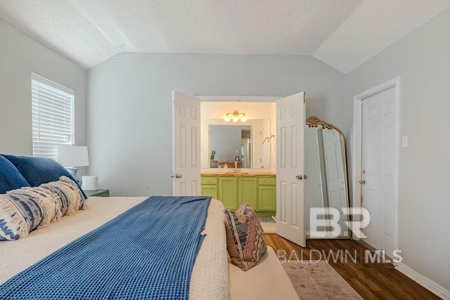 bedroom featuring ensuite bathroom, a textured ceiling, lofted ceiling, and dark wood-type flooring