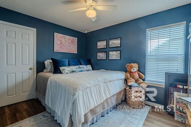 bedroom with hardwood / wood-style flooring, a textured ceiling, and ceiling fan