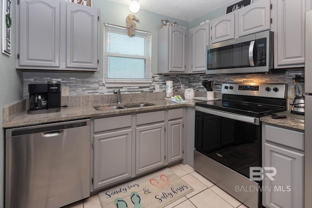 kitchen with sink, appliances with stainless steel finishes, decorative backsplash, and light tile patterned flooring