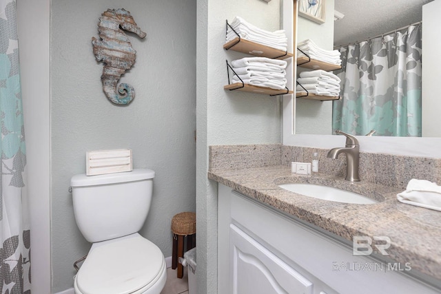 bathroom featuring vanity, toilet, and a textured ceiling