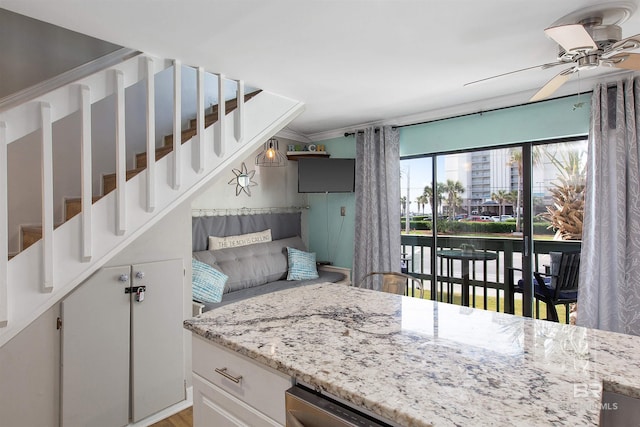 kitchen with light stone countertops, white cabinets, and a ceiling fan