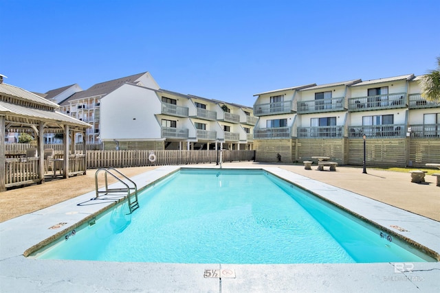 community pool featuring a patio area, fence, and a residential view