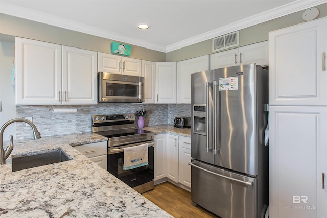 kitchen with a sink, visible vents, white cabinetry, appliances with stainless steel finishes, and crown molding