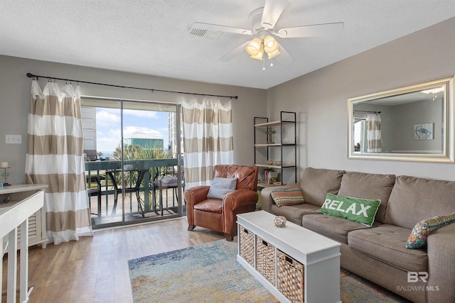 living area featuring a textured ceiling, wood finished floors, and a ceiling fan