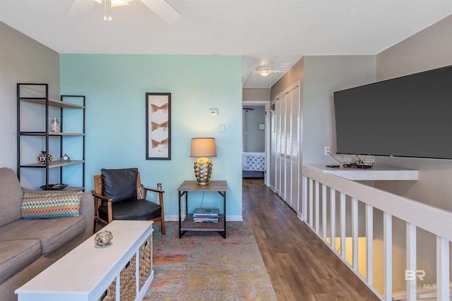 living area featuring a ceiling fan, baseboards, and wood finished floors