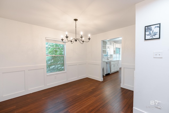 unfurnished dining area featuring sink, a notable chandelier, and dark hardwood / wood-style floors