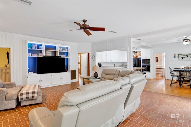 living room with ornamental molding, wood-type flooring, and ceiling fan