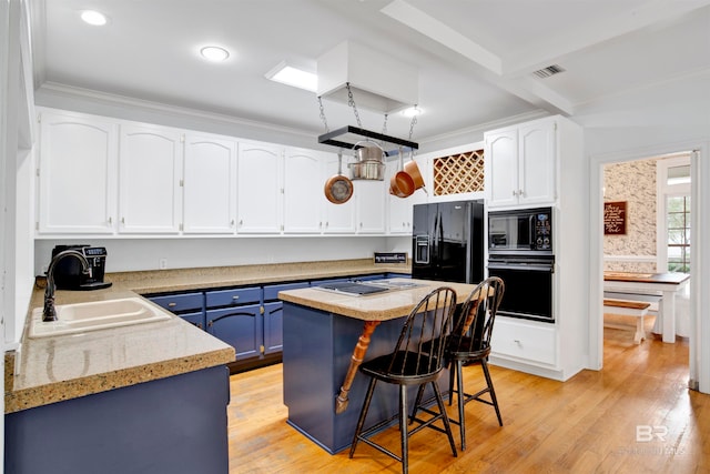 kitchen featuring white cabinets, blue cabinetry, black appliances, sink, and a center island