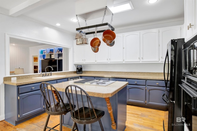 kitchen featuring sink, light wood-type flooring, a breakfast bar area, and kitchen peninsula