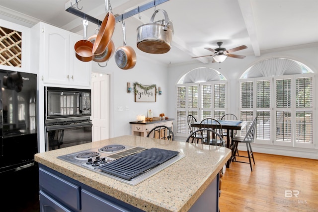 kitchen featuring a kitchen island, black appliances, light stone countertops, light wood-type flooring, and white cabinetry