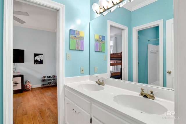 bathroom featuring hardwood / wood-style flooring, crown molding, walk in shower, vanity, and ceiling fan