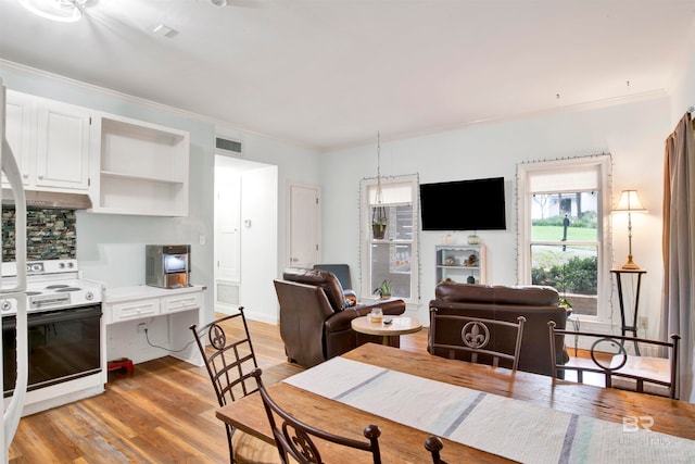 dining room with crown molding and light wood-type flooring