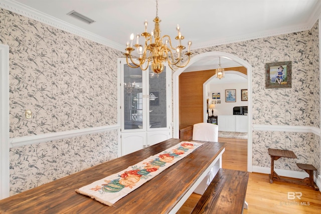 dining room with light hardwood / wood-style floors and crown molding